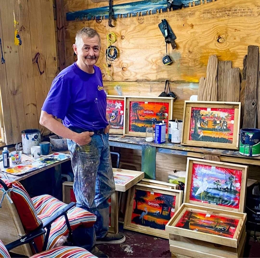Rodney Lewis standing in his workshop with framed swamp paintings